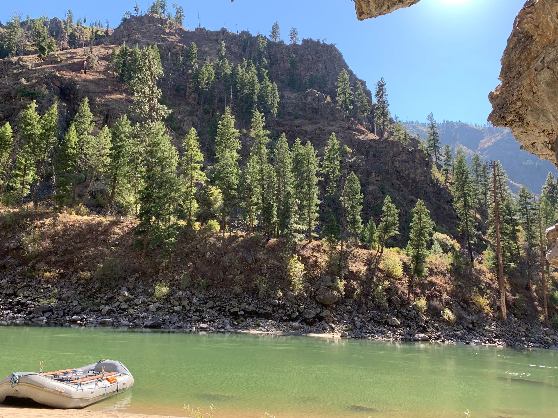 A boat is sitting on the shore of a river surrounded by trees.