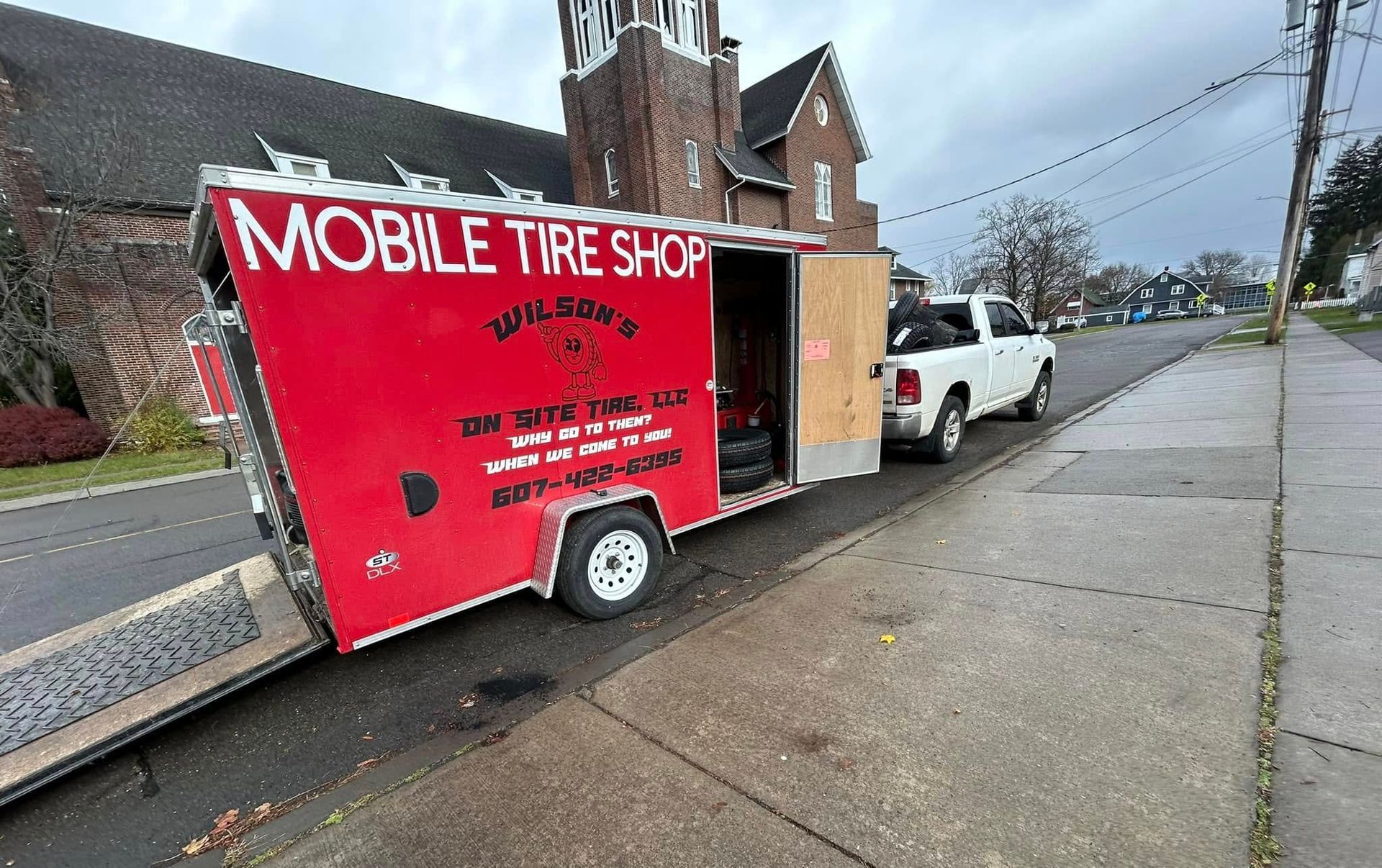 A mobile tire shop trailer is parked on the side of the road.