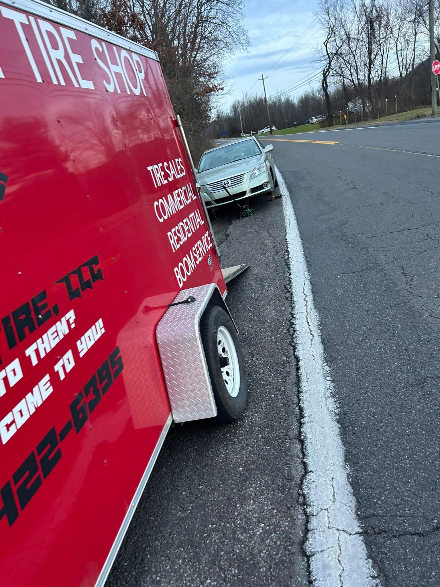 A red trailer is parked on the side of the road next to a car.