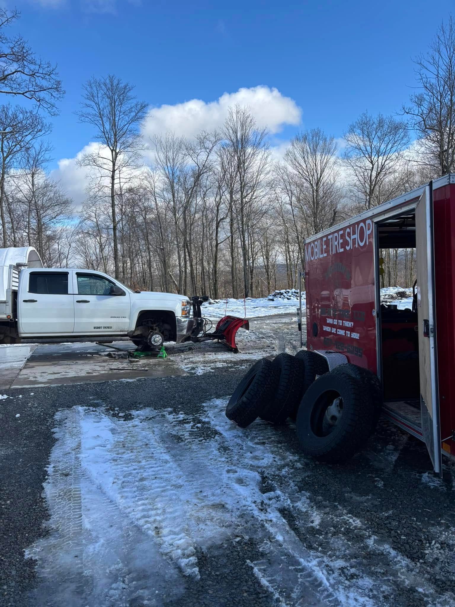 A white truck is parked next to a red trailer in the snow.