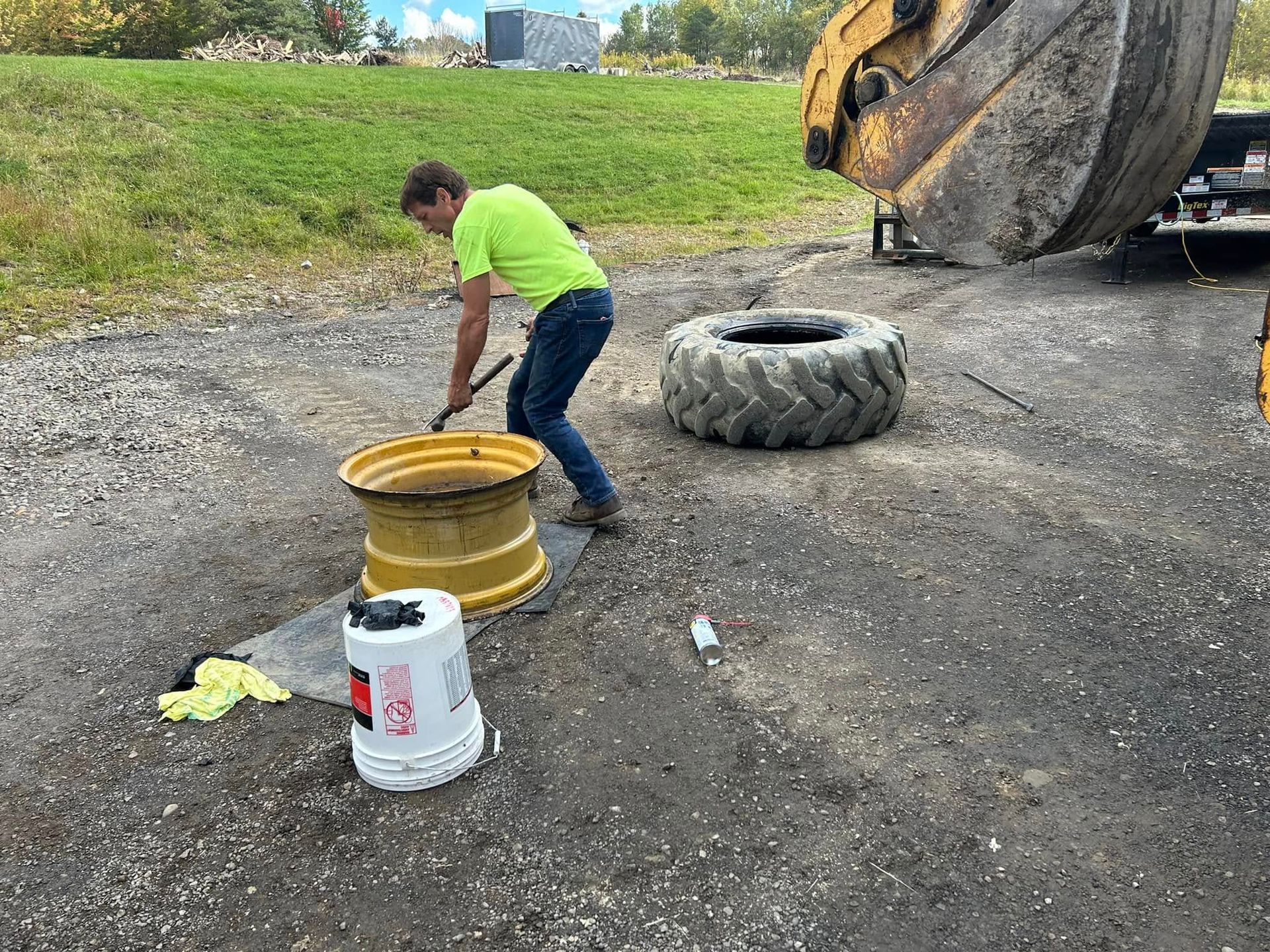 A man is cleaning a tire with a broom in a parking lot.