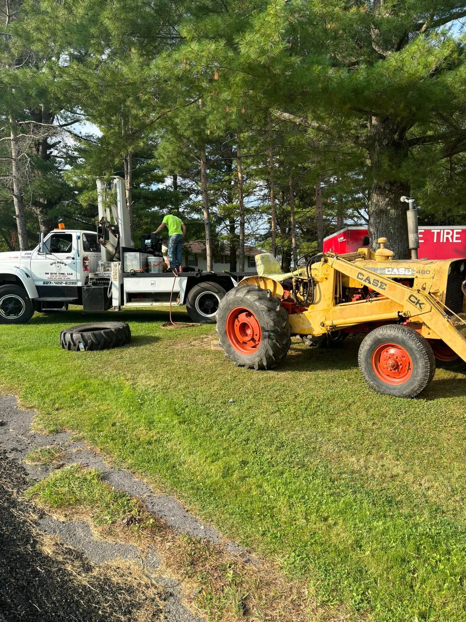 A yellow tractor is parked next to a white truck in a grassy field.