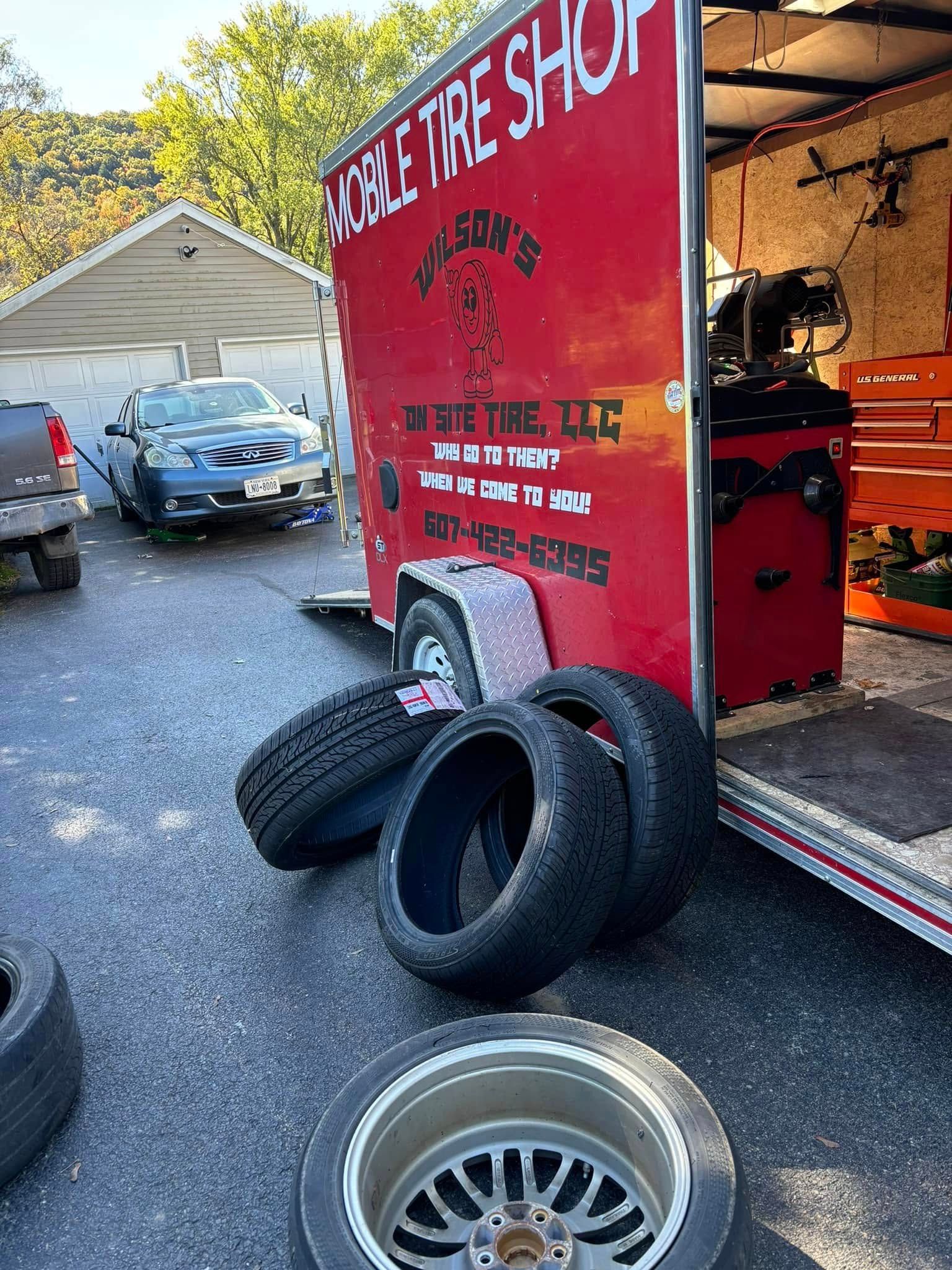 Tires are stacked on top of each other in front of a tire shop trailer.