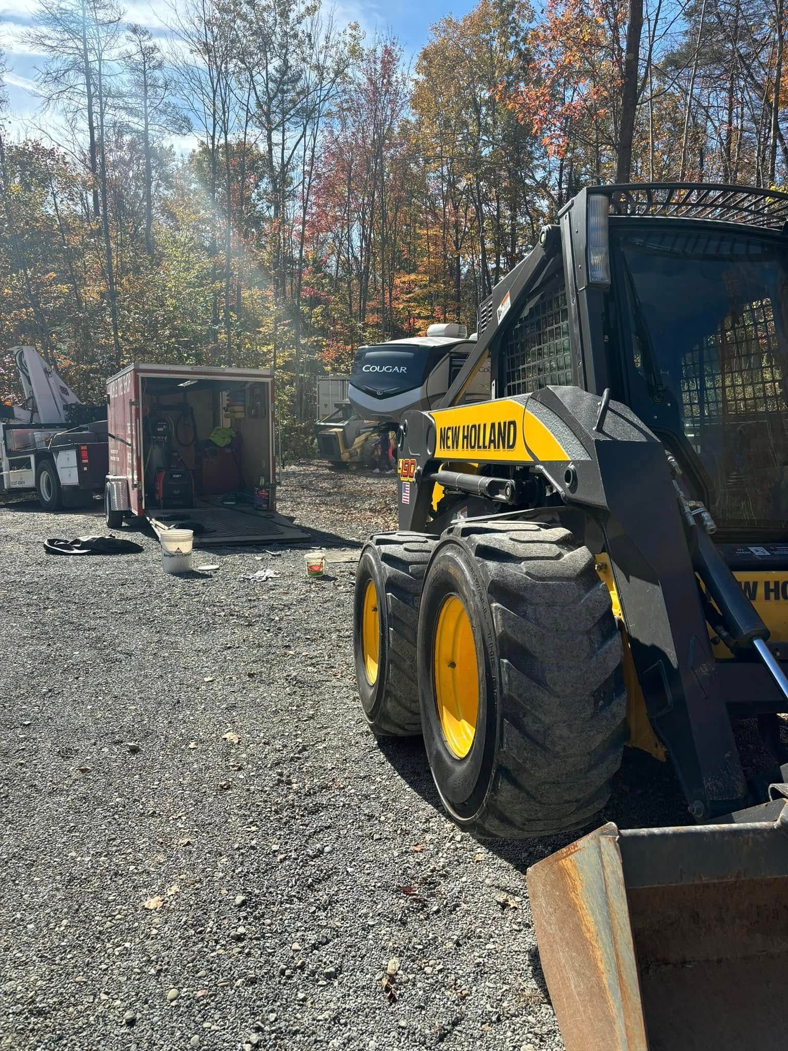 A yellow and black tractor is parked in a gravel lot.