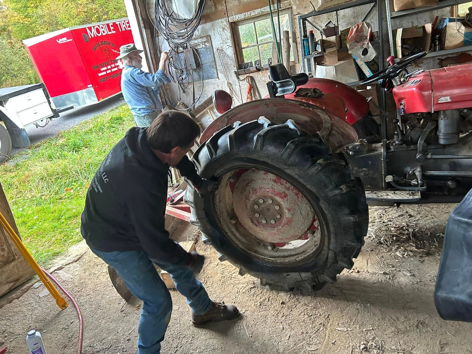 A man is working on a tractor in a garage.