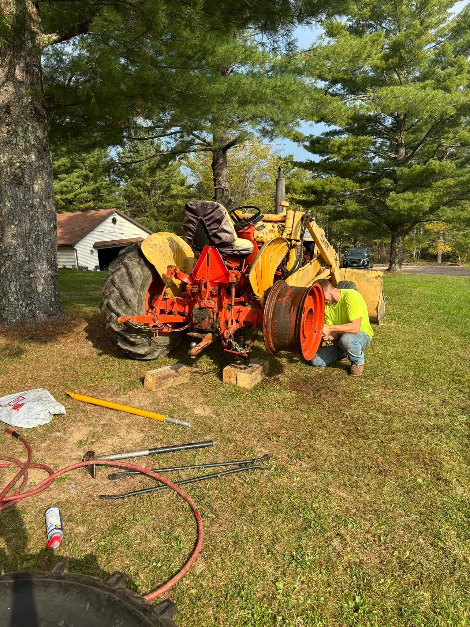 A man is working on a tractor in a grassy field.