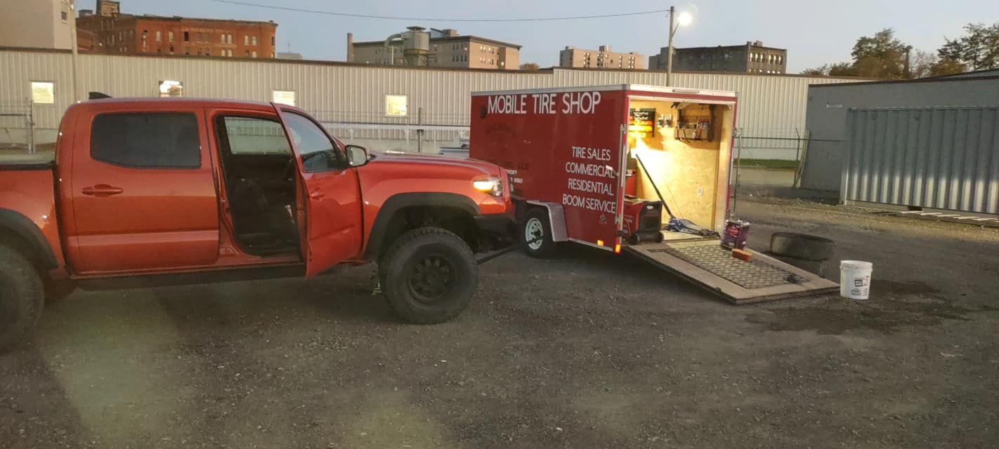A red truck is parked next to a trailer in a parking lot.