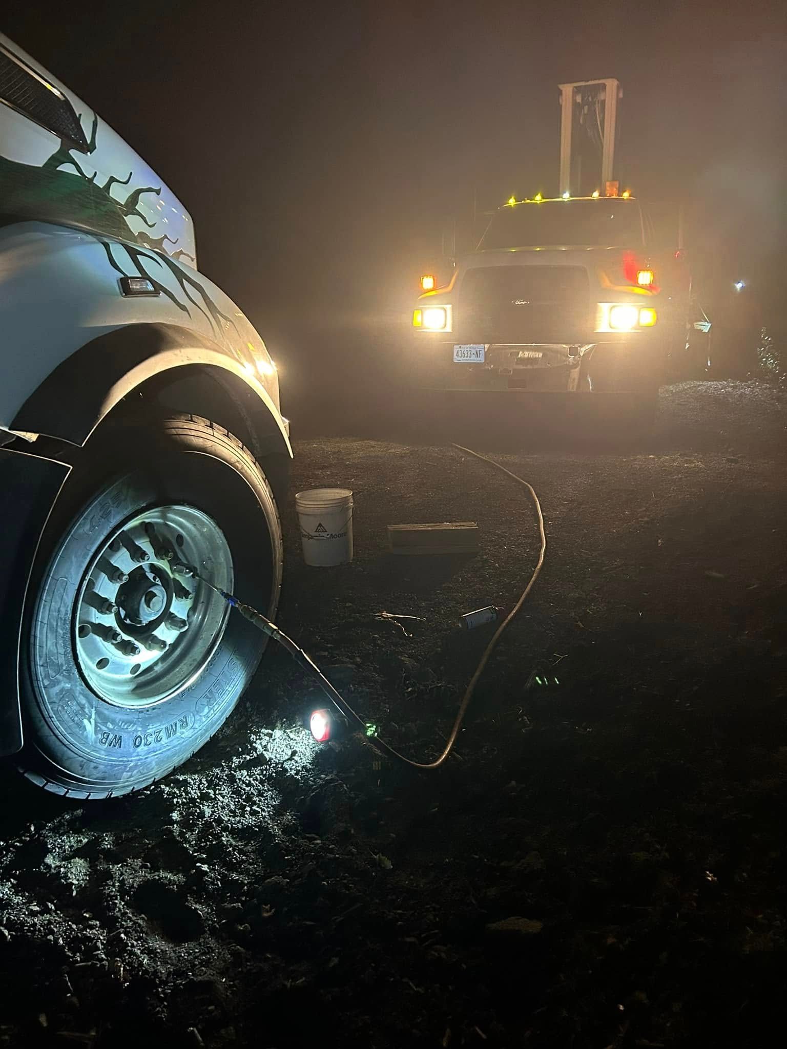 A truck is being towed by another truck at night