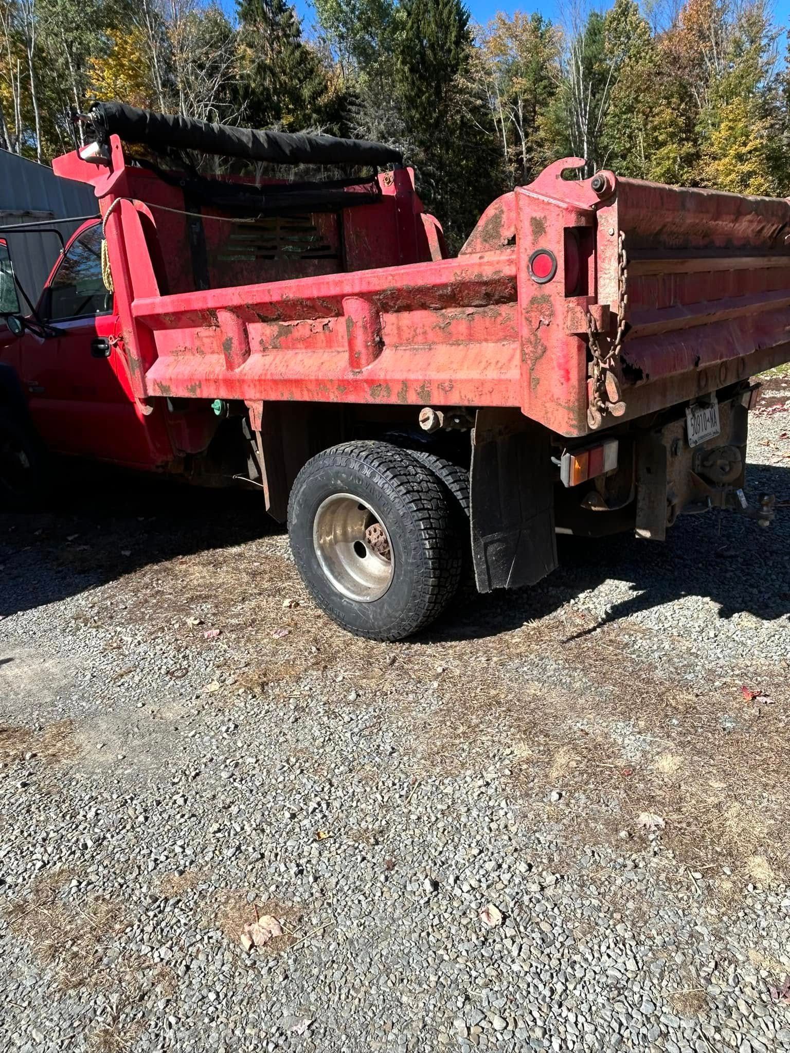 A red dump truck is parked in a gravel lot.