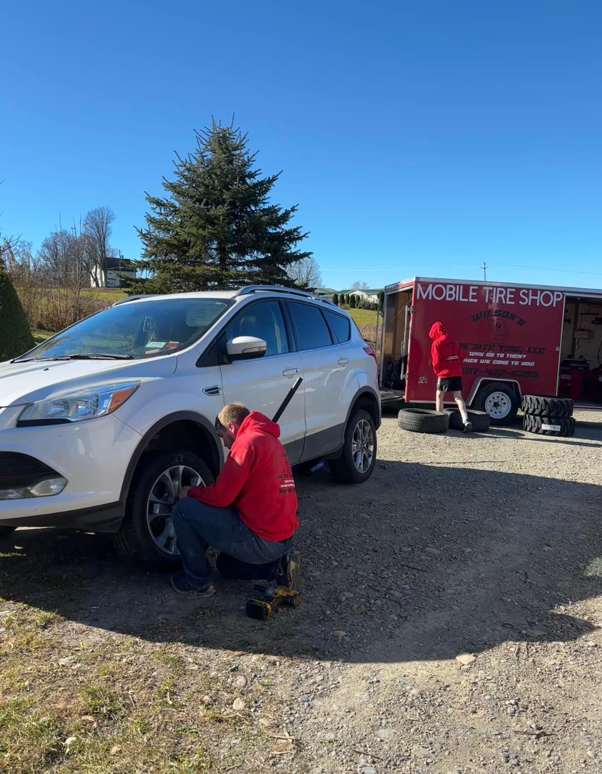 A man is changing a tire on a white suv.