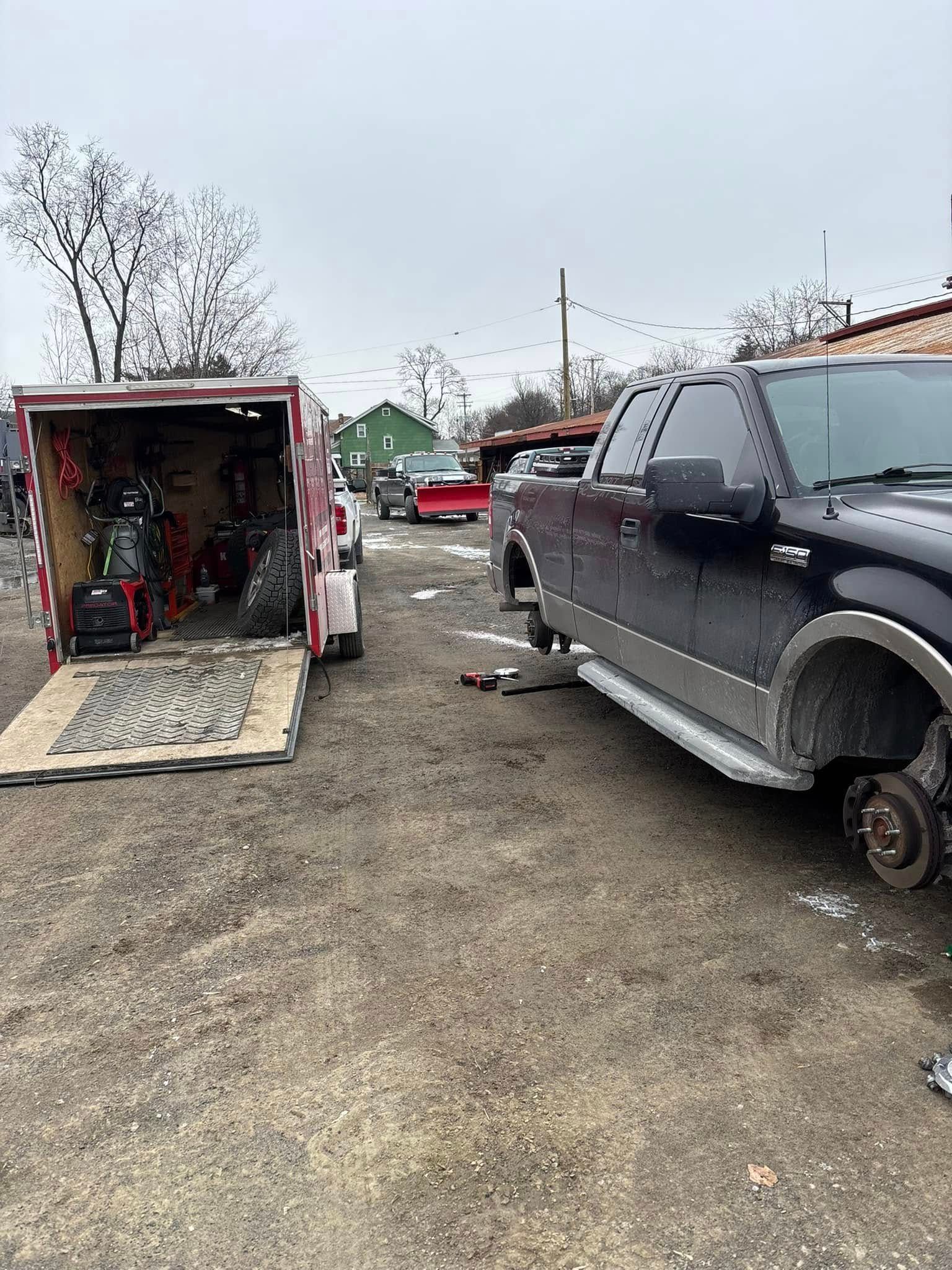 A truck is parked next to a trailer with a motorcycle in it.