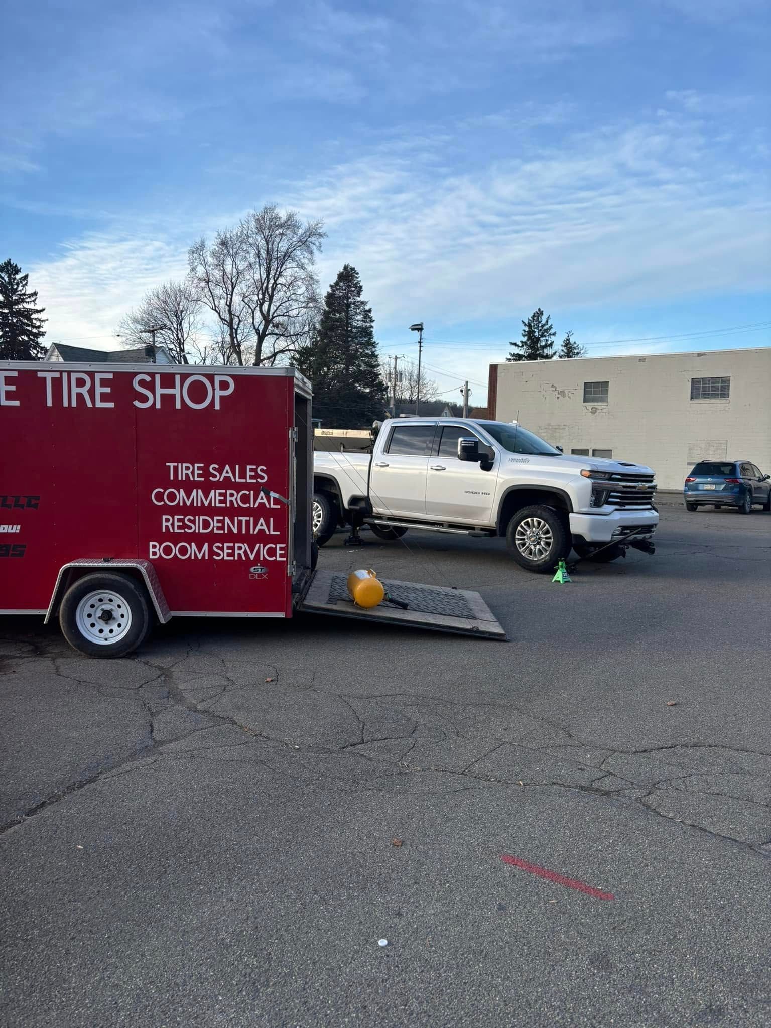 A white truck is parked next to a red trailer in a parking lot.
