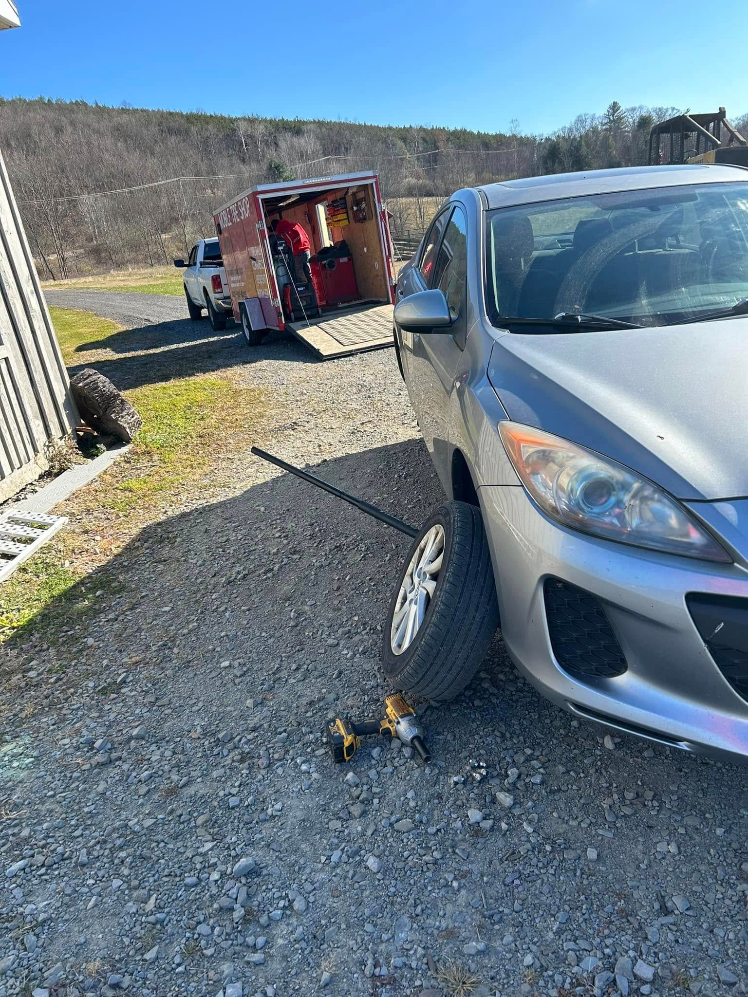 A car is sitting on a gravel road next to a truck.