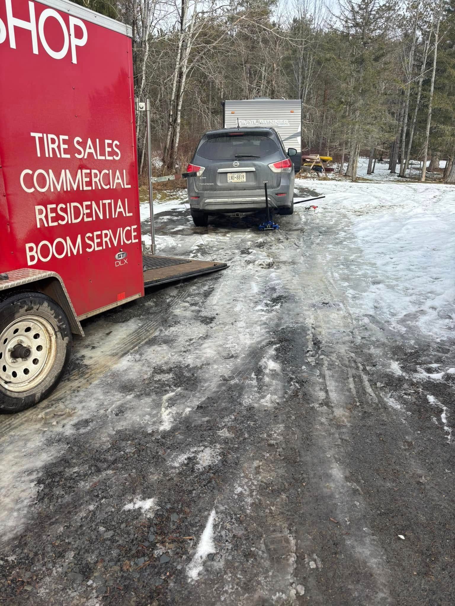 A car is being towed by a red trailer in the snow.