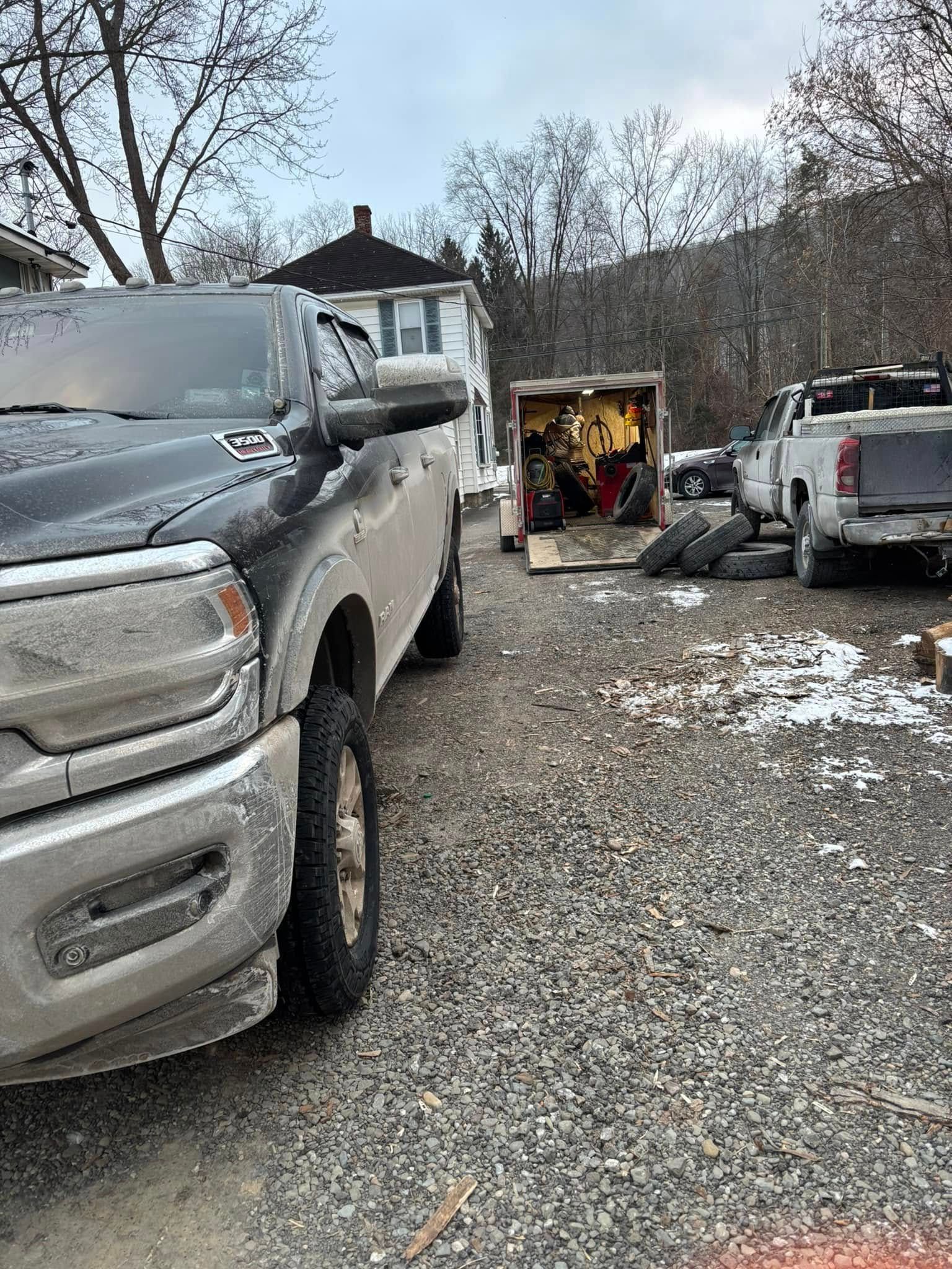 A black truck is parked in a gravel lot next to a white truck.