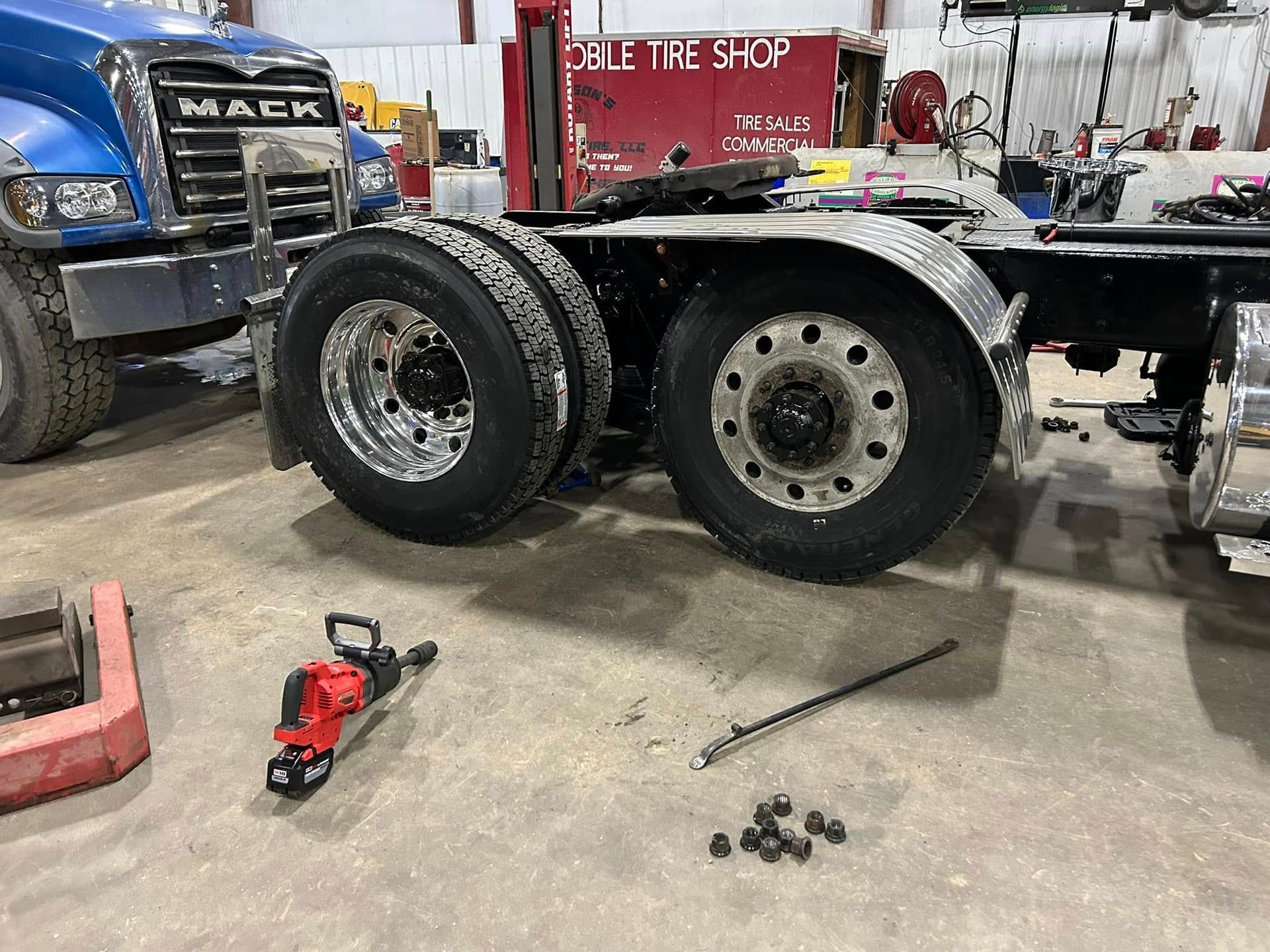 A semi truck is being worked on in a garage.