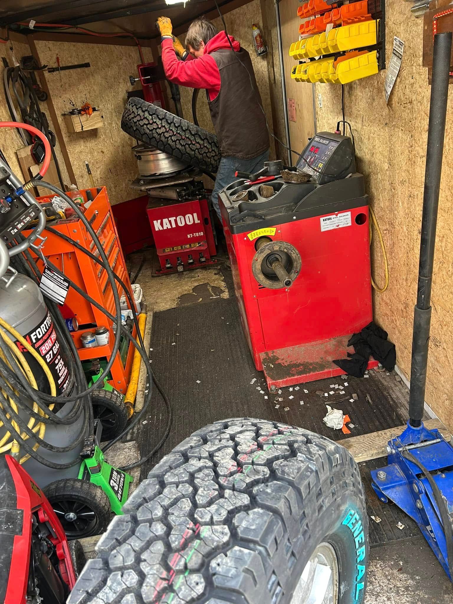 A man is balancing a tire in a garage.