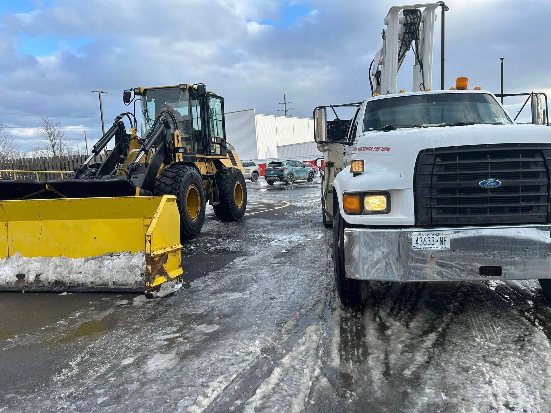 A snow plow and a truck are parked next to each other on a snowy road.