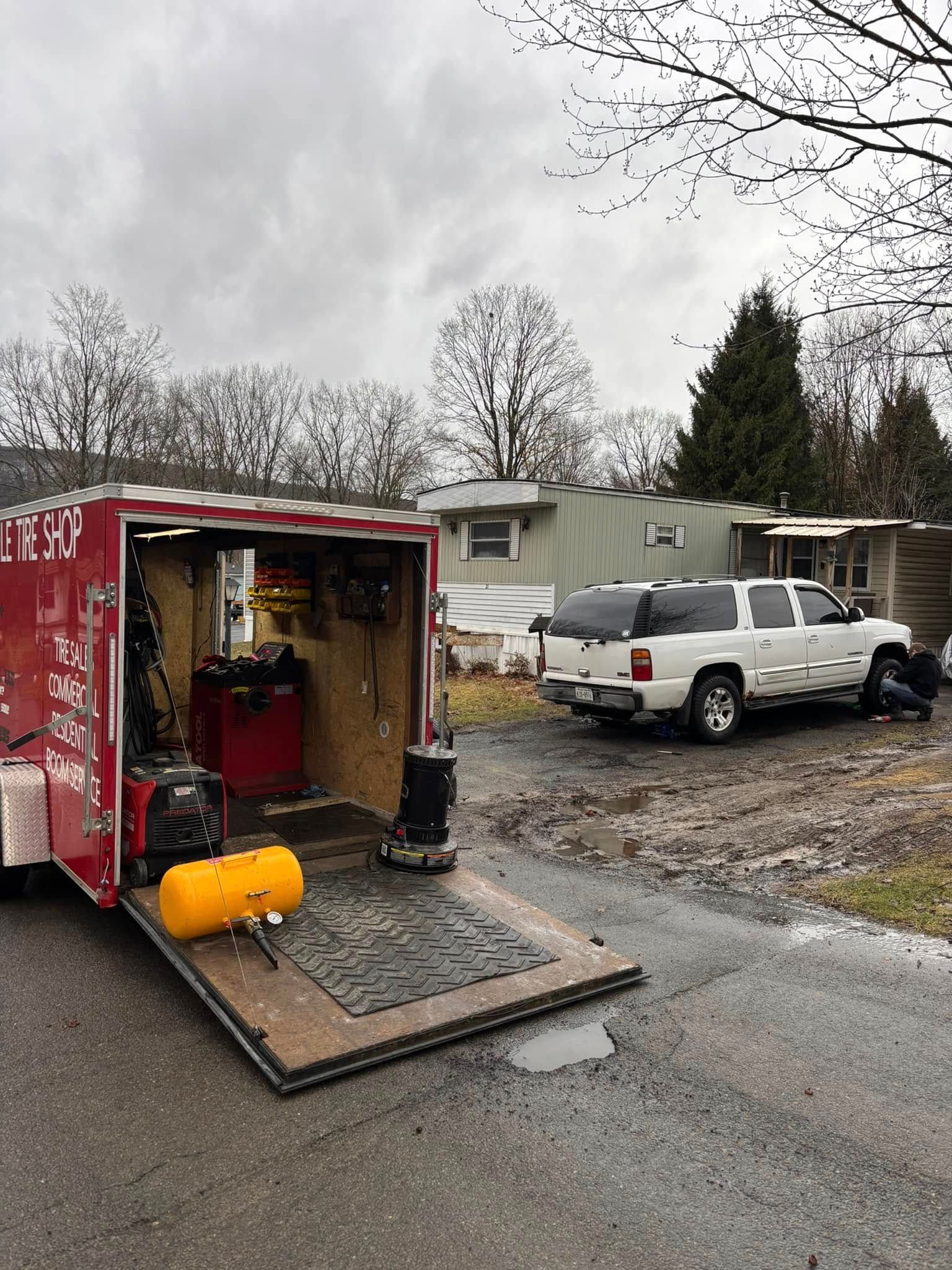 A red trailer is parked on the side of the road next to a white truck.