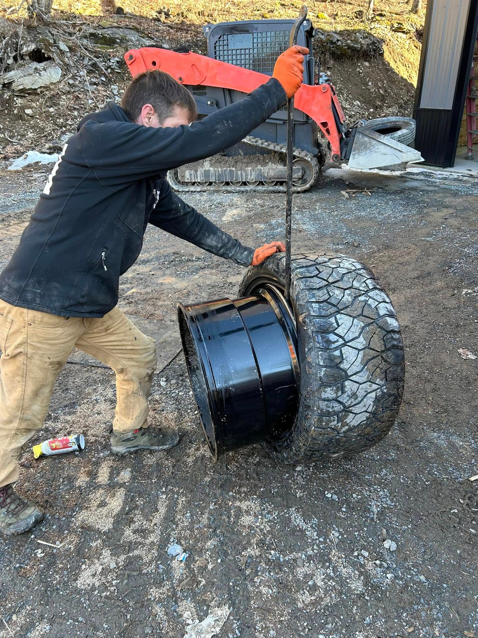 A man is standing next to a large tire.