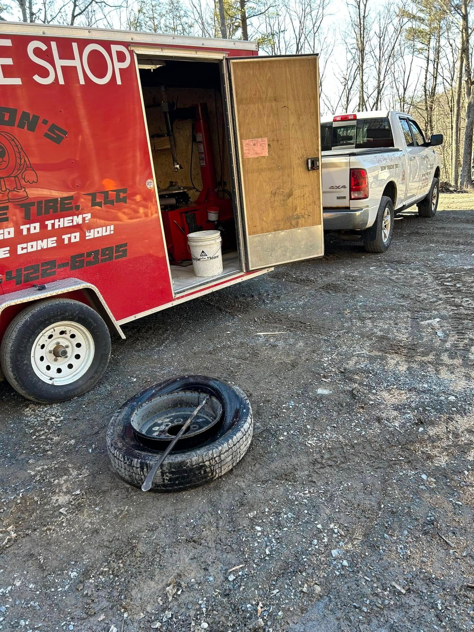 A truck is parked next to a trailer that says tire shop.