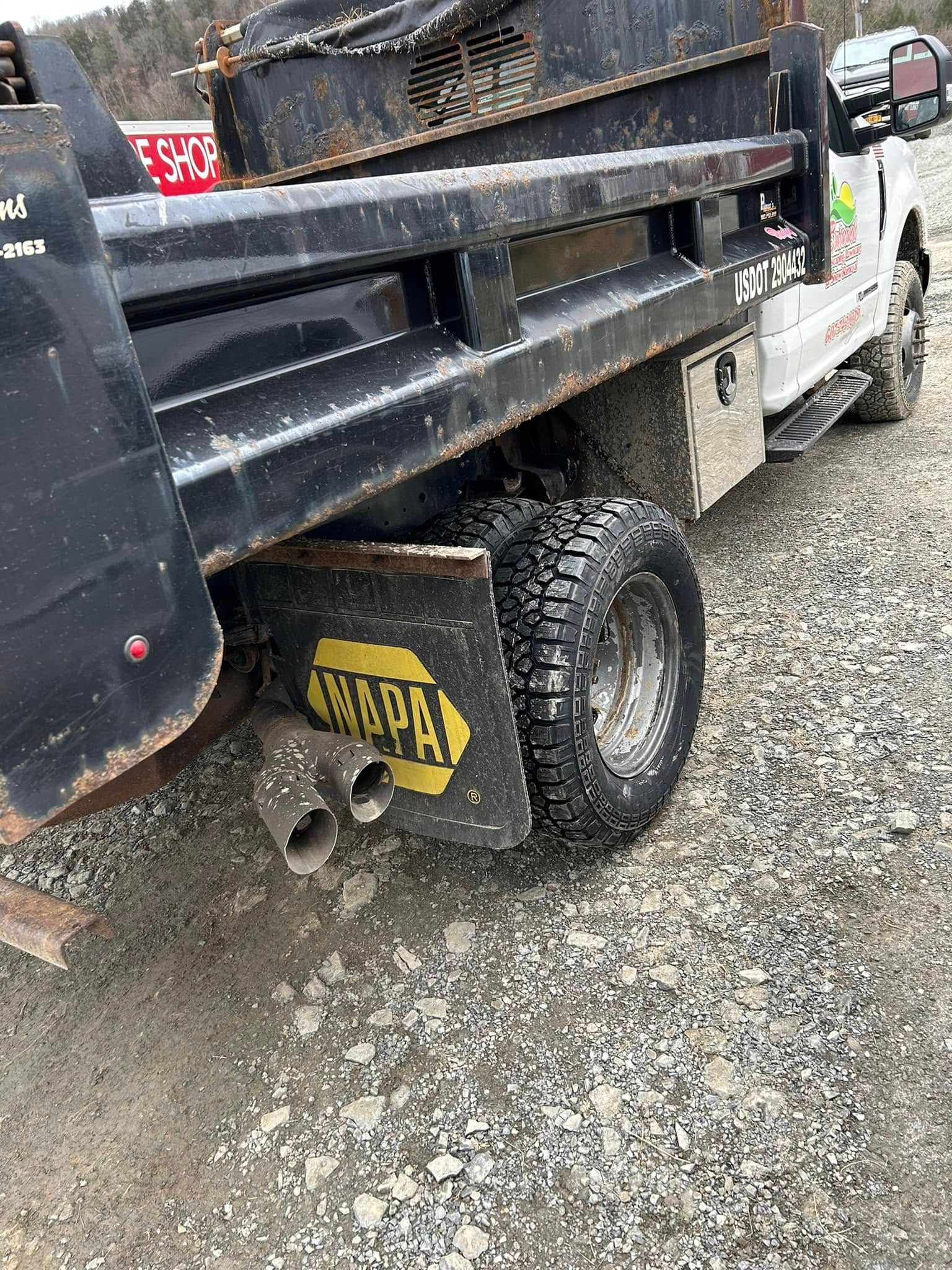 A dump truck is parked on a gravel road.