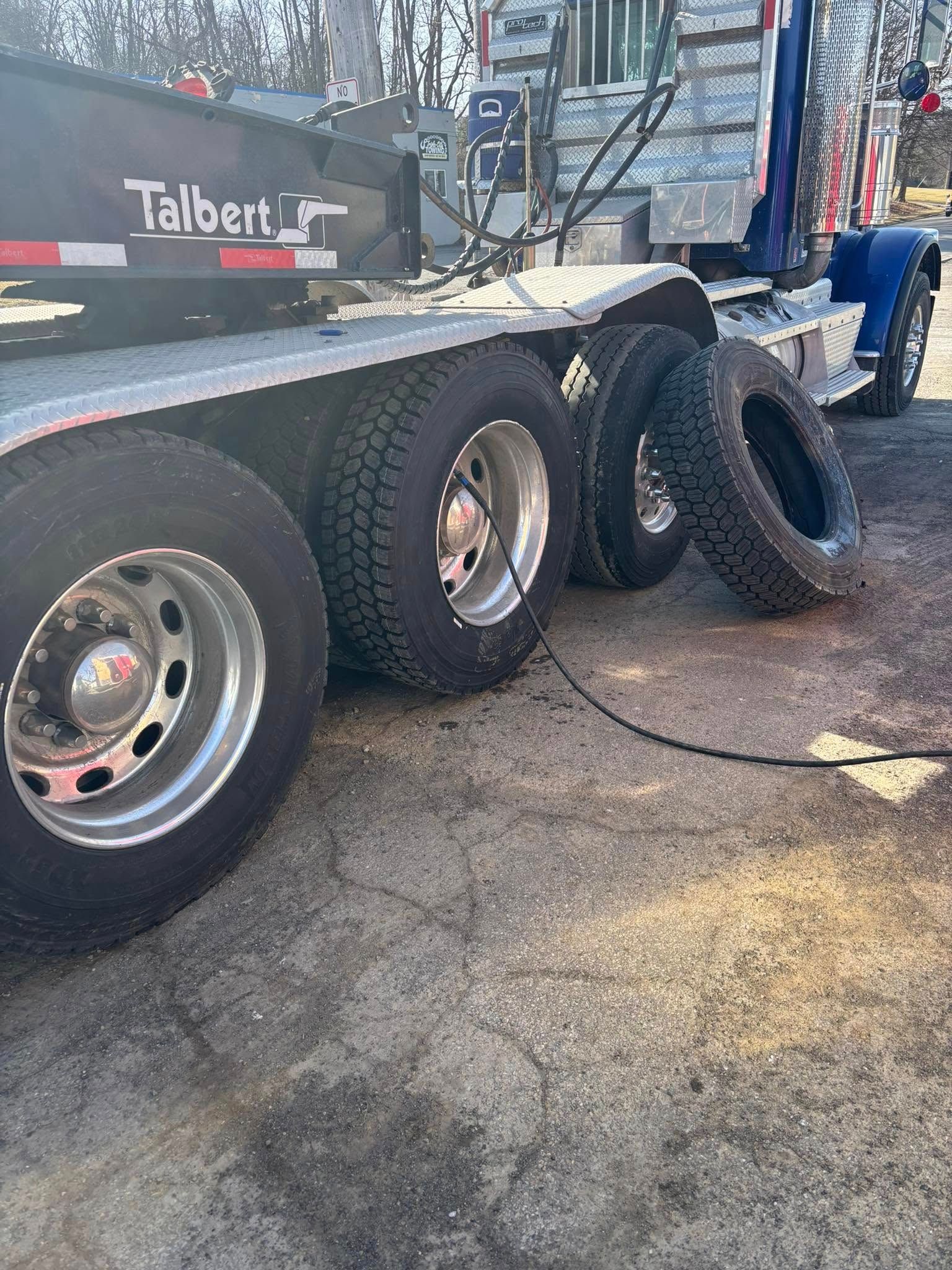 A semi truck with tires attached to it is sitting on the ground.