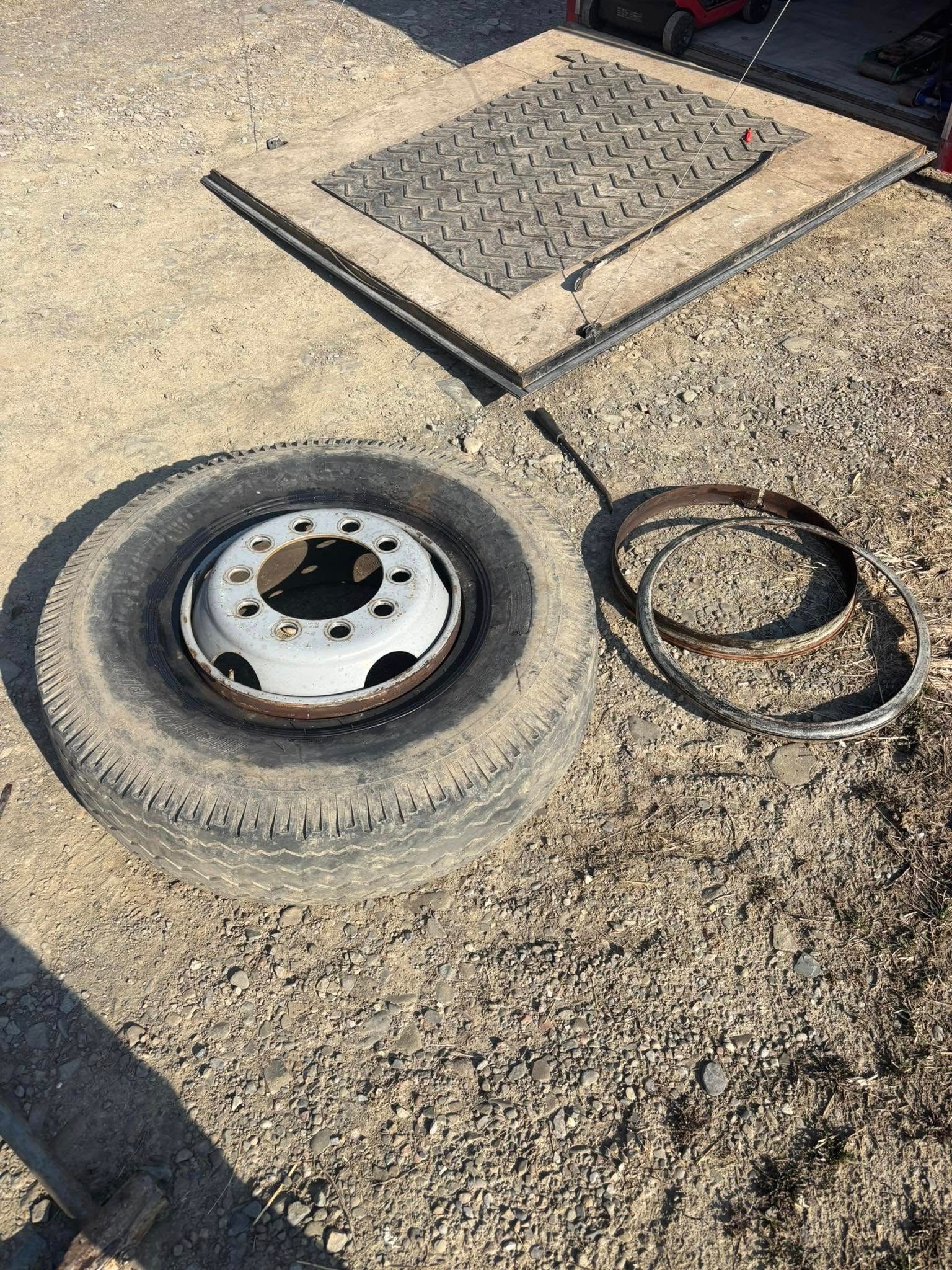 A tire is sitting on the ground next to a metal rim.