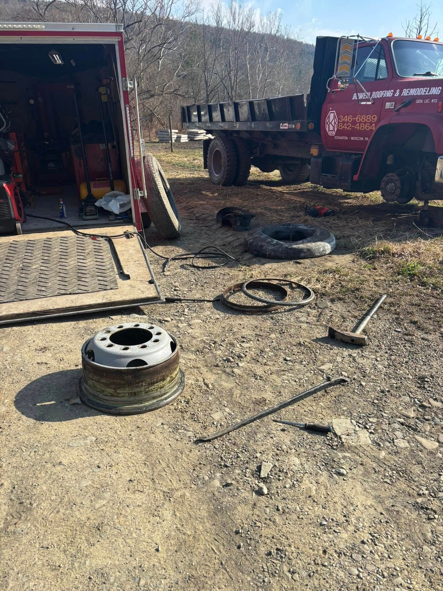A red truck is sitting in the dirt next to a tire.