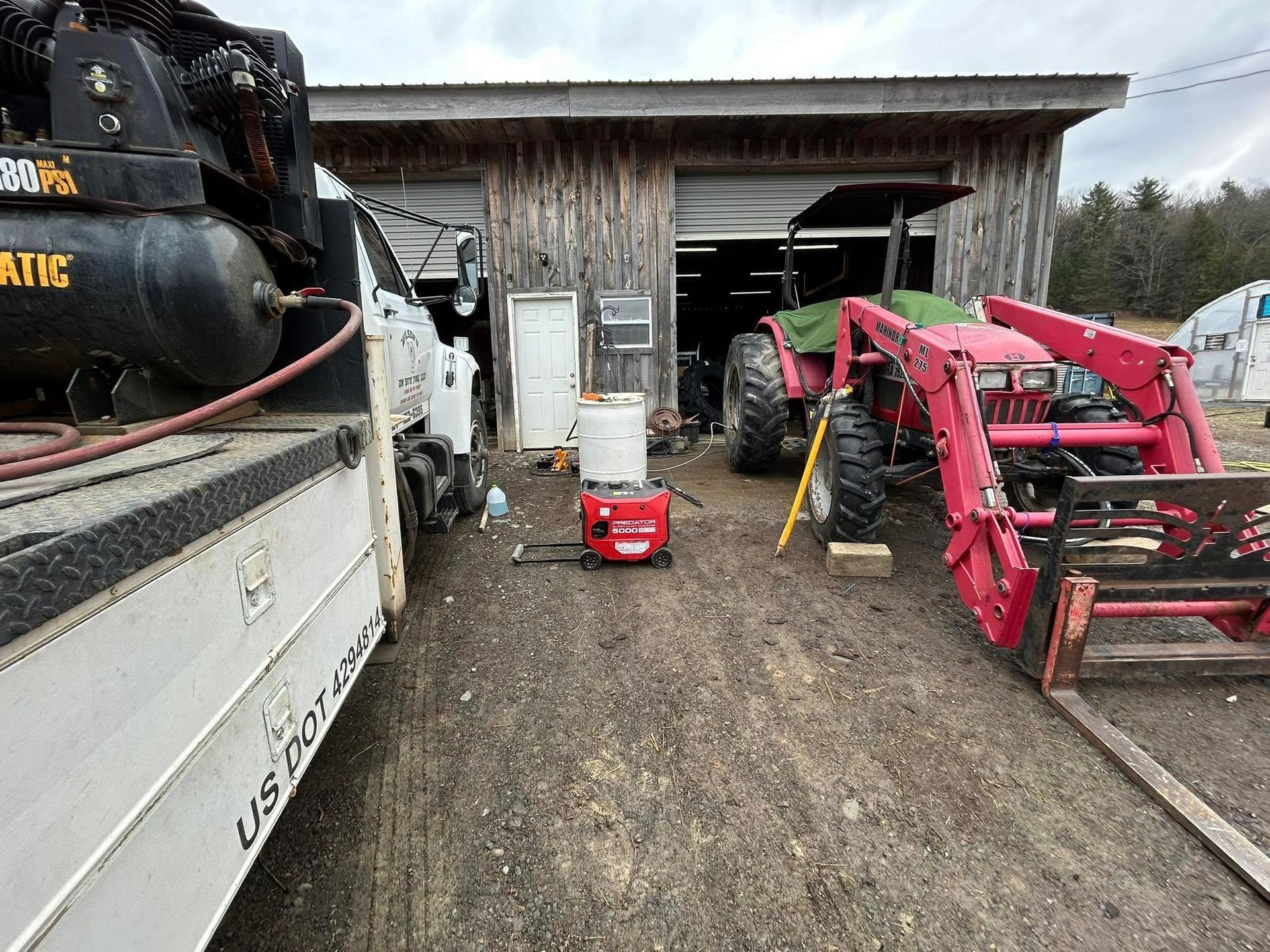A red tractor is parked in front of a garage.
