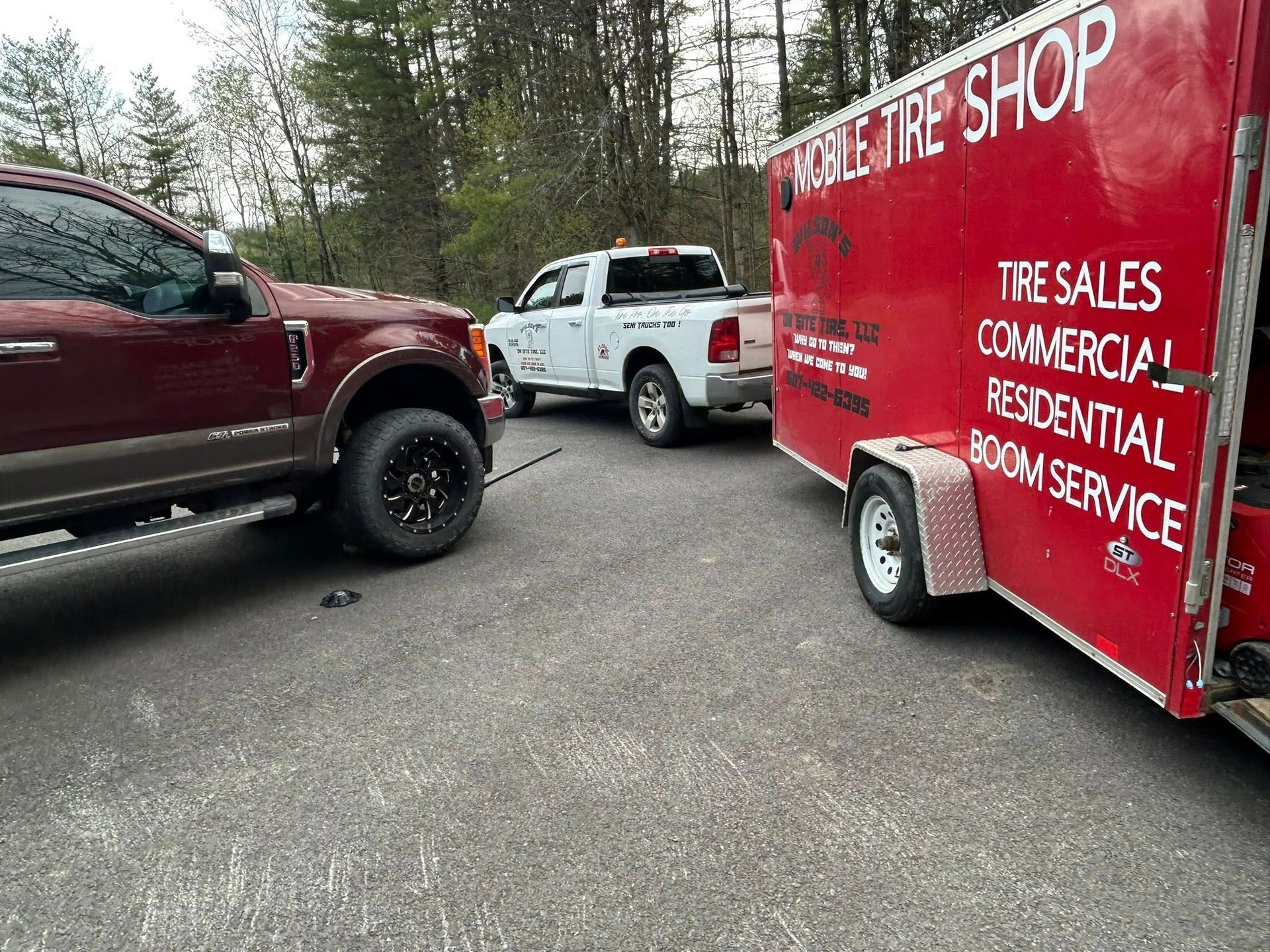 A red truck is towing a red trailer that says mobile tire shop.