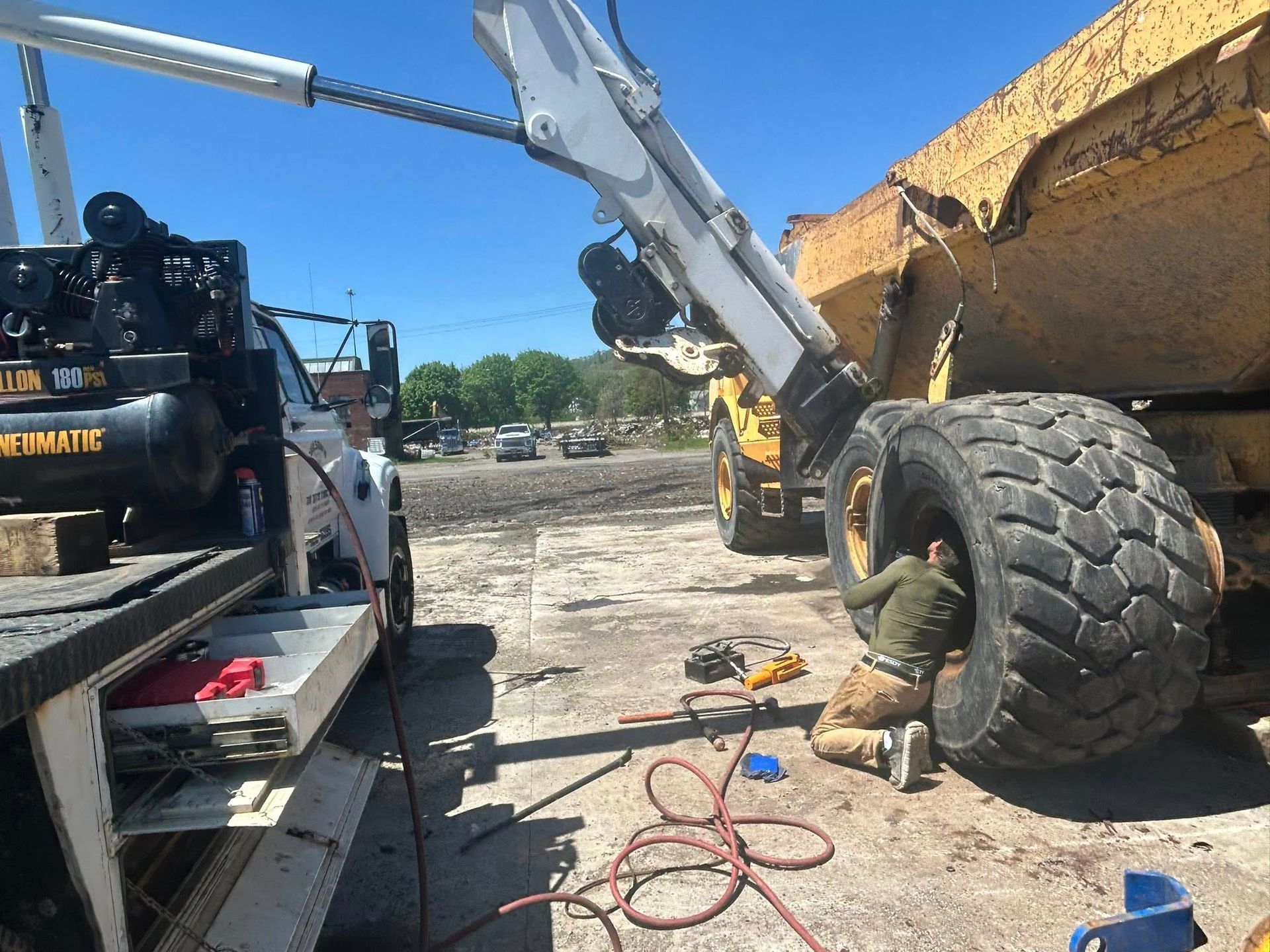 A man is working on a large tire on a dump truck.