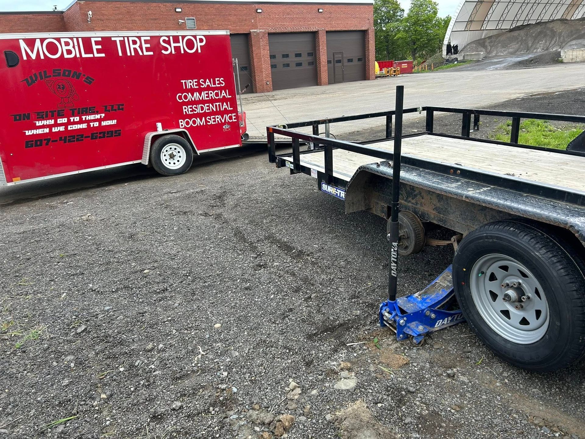 A mobile tire shop truck is parked next to a trailer.