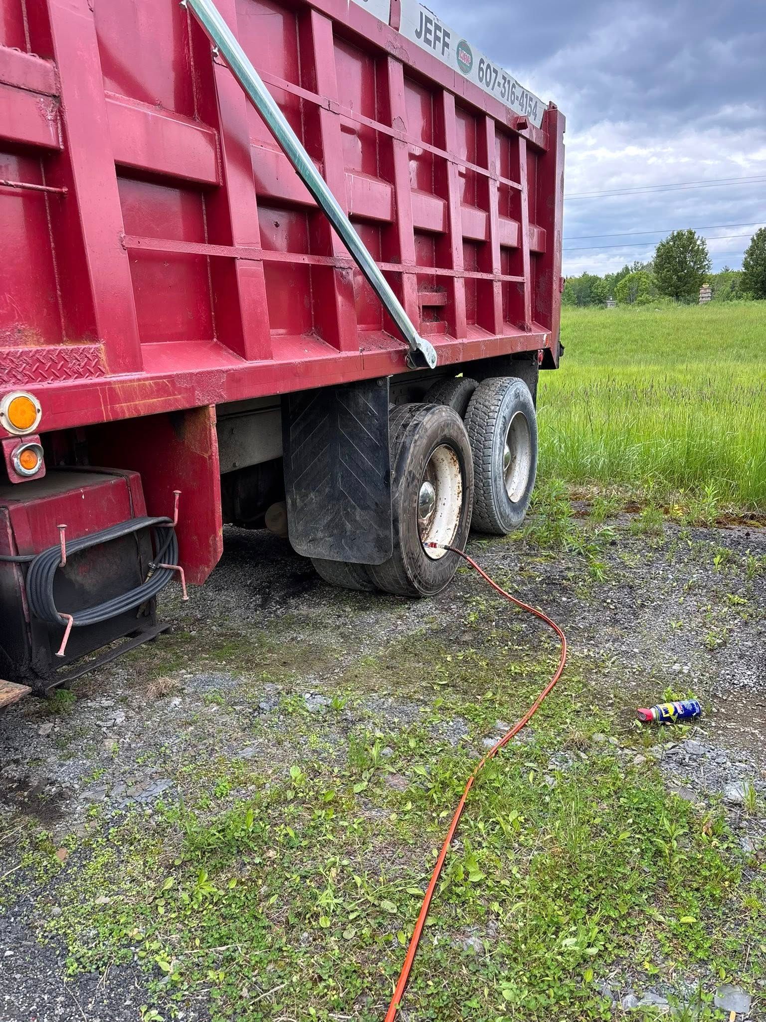 A red dump truck is parked in a grassy field.