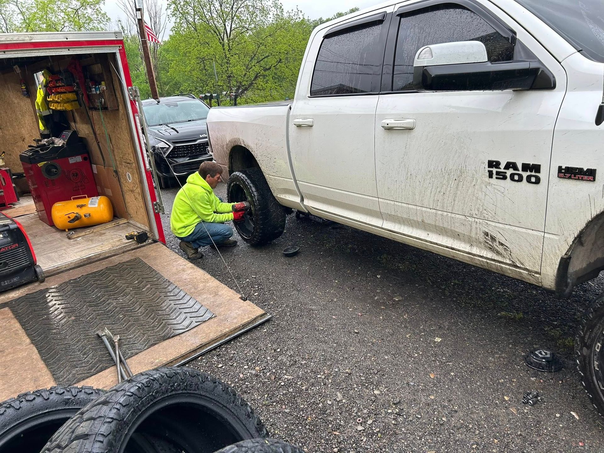 A man is changing a tire on a white truck.