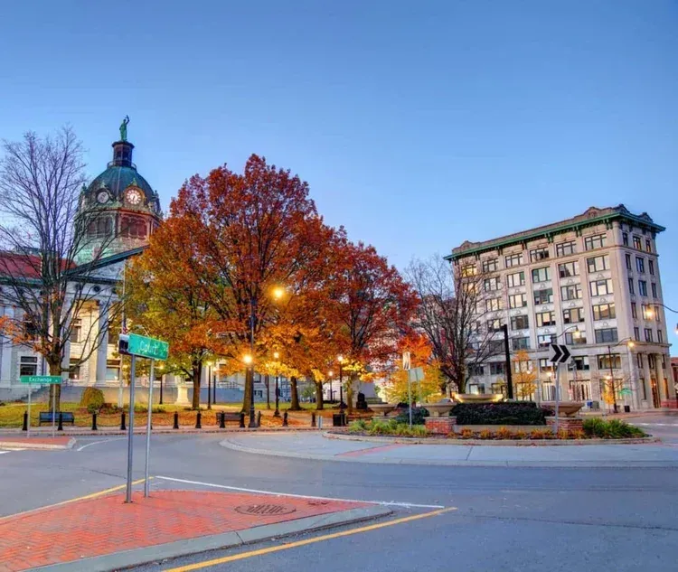 Cityscape with courthouse dome, fall foliage, and building at dusk.