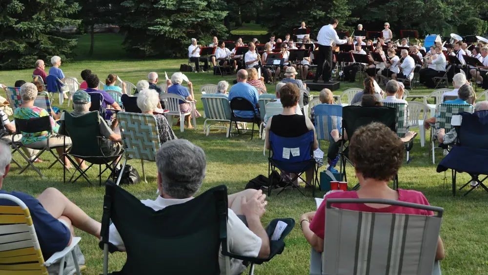 An outdoor concert; a band performs for seated audience on lawn.