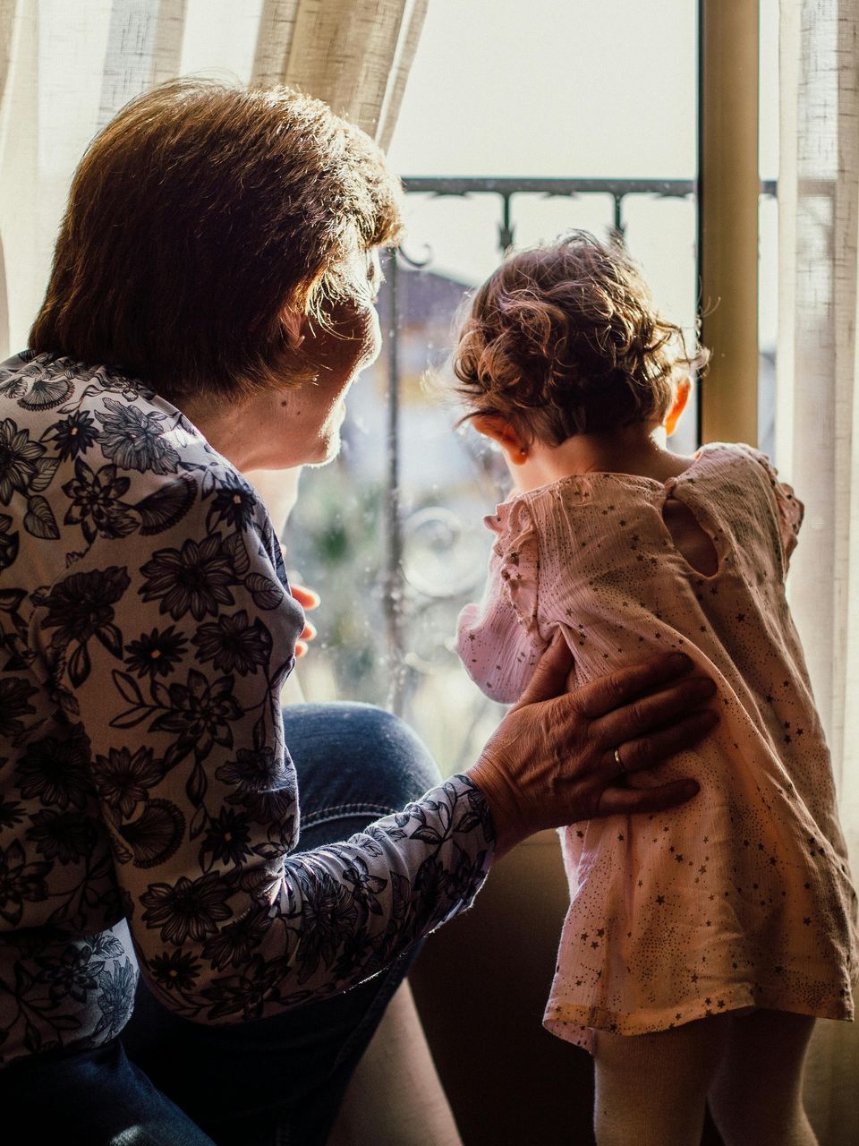 A little girl is holding the hand of her grandparents while walking in a field.