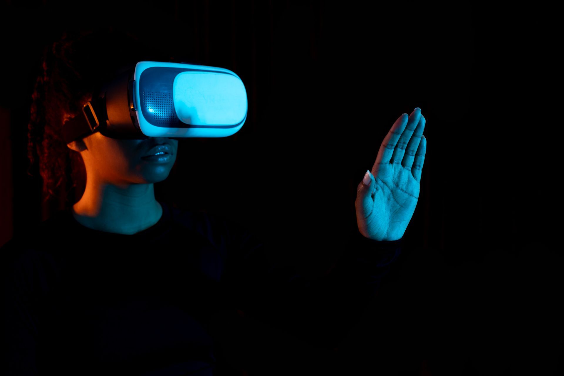 A person is wearing a virtual reality headset and touching a hand.