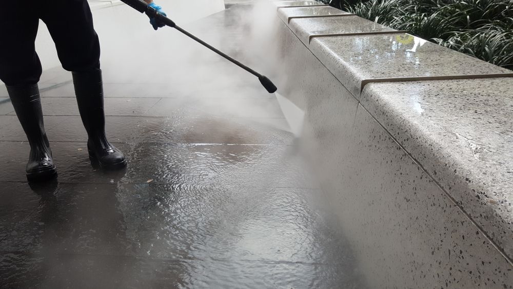 A Person is Using a High Pressure Washer to Clean a Sidewalk — Hire Power NT in Berrimah, NT