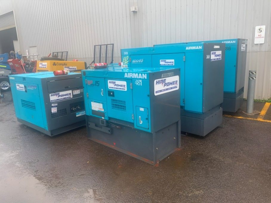 Three Blue Generators Are Parked in a Parking Lot in Front of a Building — Hire Power NT in Berrimah, NT