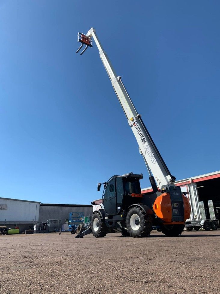 A Telescopic Crane is Parked in a Gravel Lot in Front of a Building — Hire Power NT in Berrimah, NT
