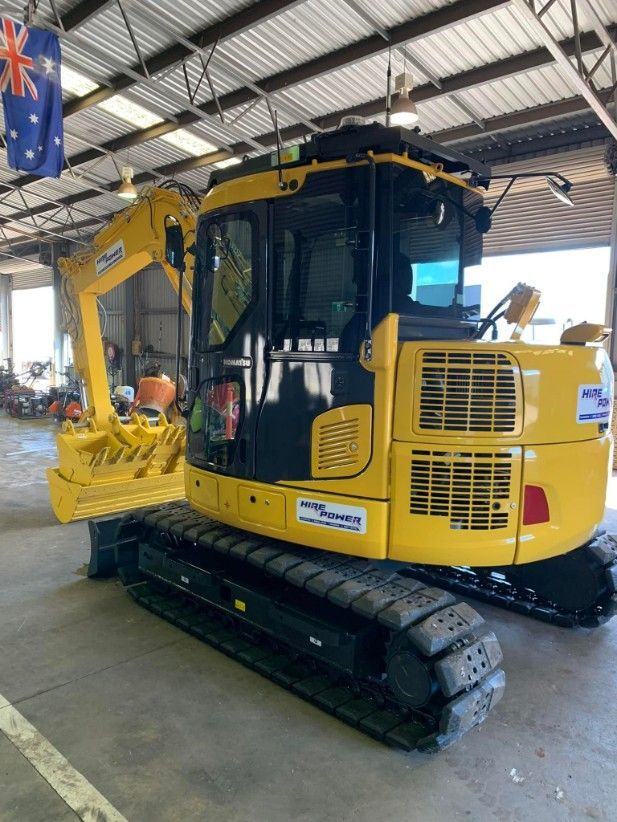 A Yellow and Black Excavator is Parked in a Garage — Hire Power NT in Berrimah, NT