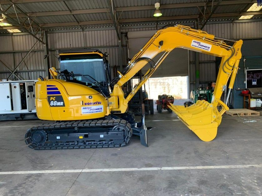 A Yellow Excavator is Parked in a Garage — Hire Power NT in Berrimah, NT