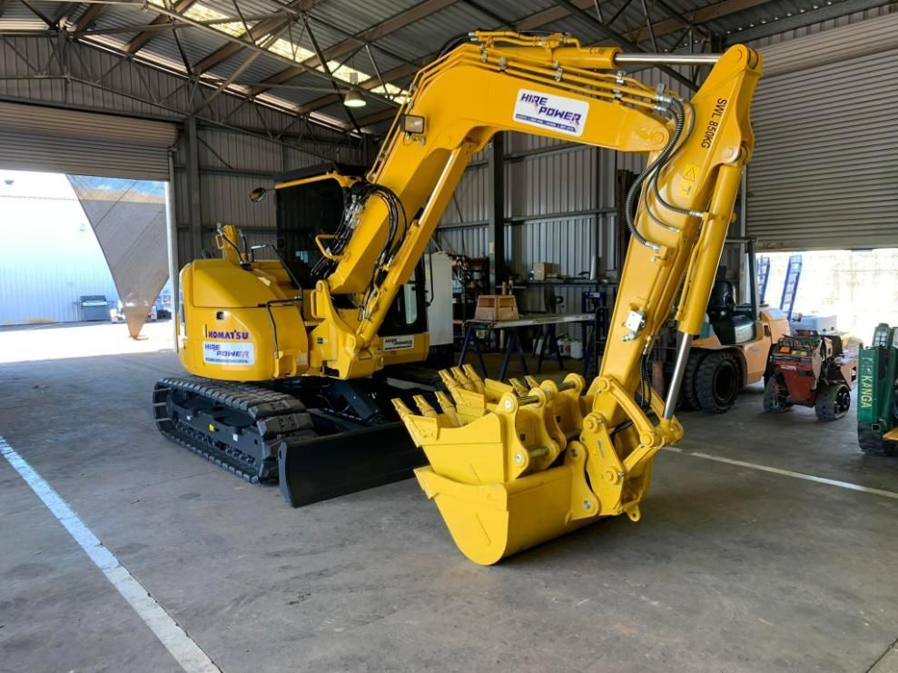 A Yellow Excavator is Parked in a Garage — Hire Power NT in Berrimah, NT