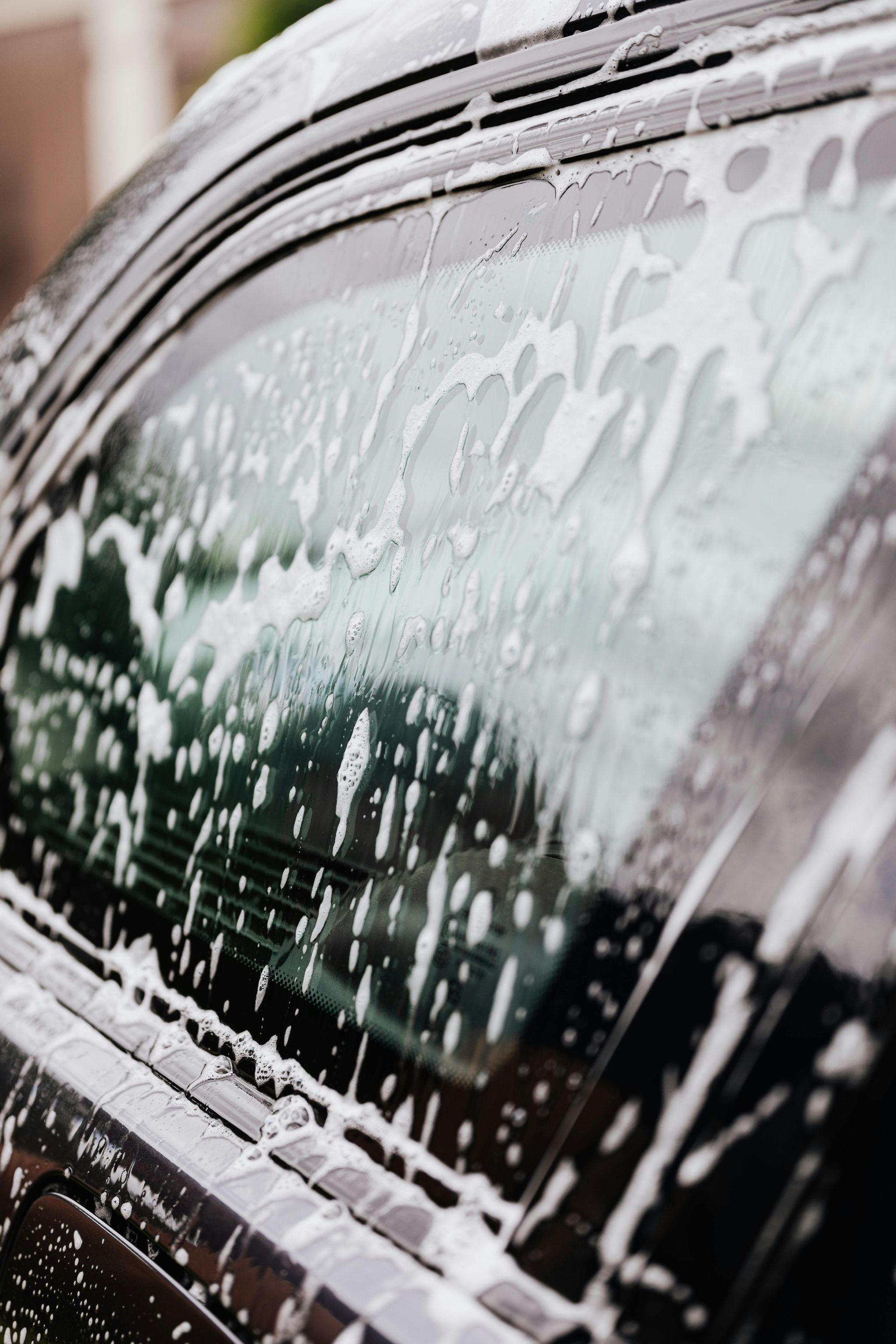 A black car is being washed with soap and water.