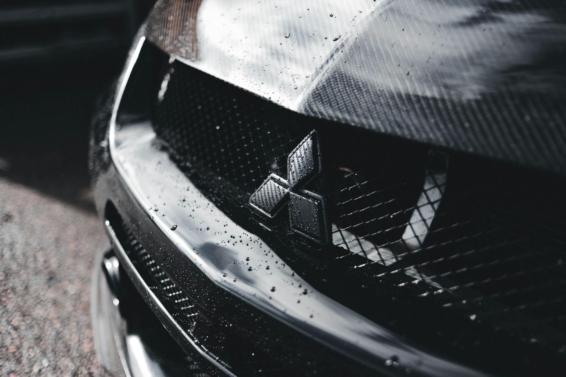 A close up of the front of a black car with a mitsubishi logo on it.