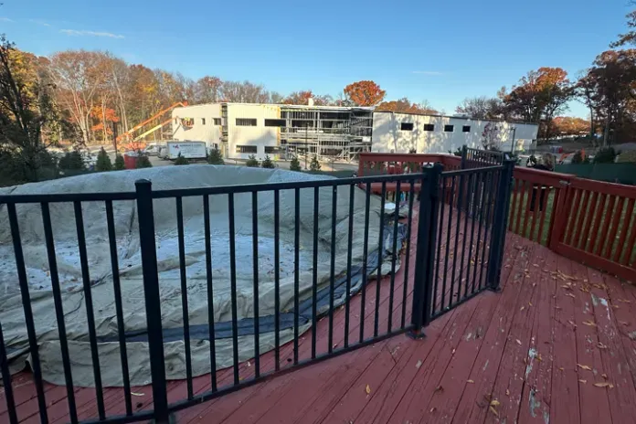 Aboveground pool with cover on it. Background shows massive warehouse and no trees, forest, or other natural elements.