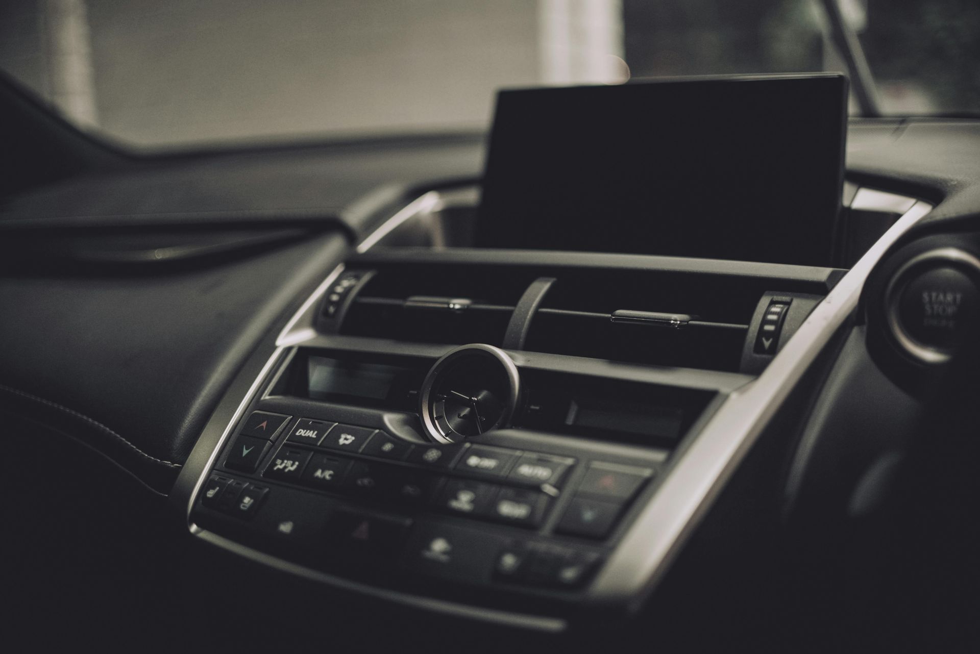 Car climate control panel with illuminated buttons and chrome trim.