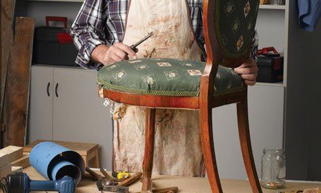 a carpenter repairing an antique furniture's leg